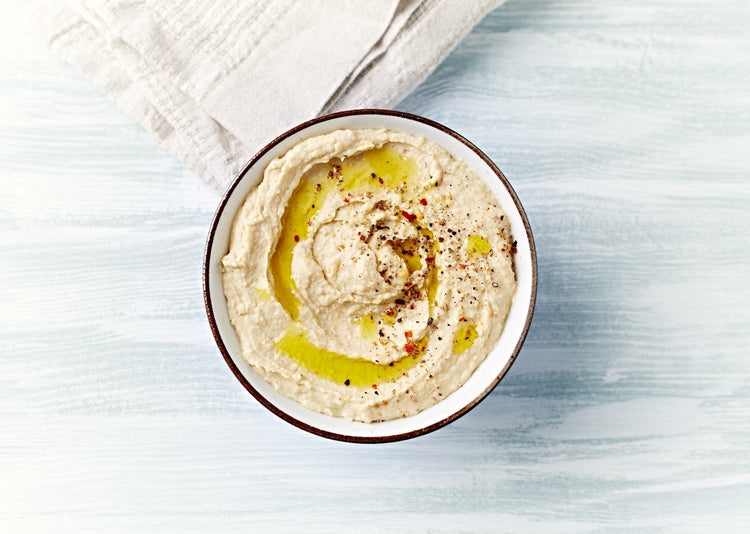 a bowl of hummus on a plain background 