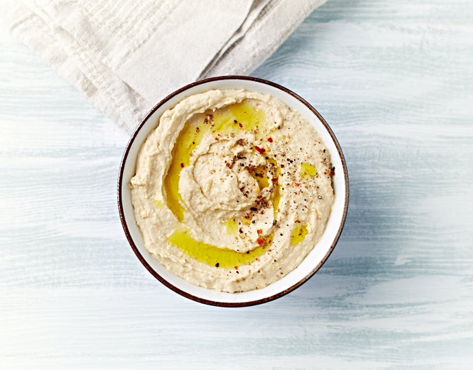 a bowl of hummus on a plain background 