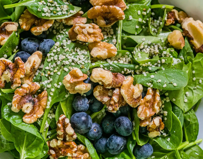 A Spinach, Blueberry and Walnut Salad in a white bowl
