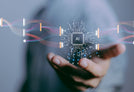 A person's hand is extended forward, with a floating microchip labeled "AI" in the center. The microchip is connected to lines symbolizing data flow, merging and splitting with other chips. The background is blurred, drawing focus to the AI element in the hand.