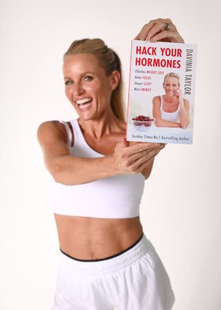 Davinia Taylor holding her book Hack Your Hormones on a white background