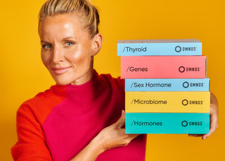 Davinia Taylor holding multiple coloured books, on an orange background