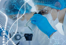 A scientist in a lab coat, gloves, and protective eyewear is looking into a microscope. There is a blue double helix DNA model and chemical formulas overlaid on the image