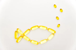 A fish shape is made using yellow translucent capsules on a white background, with smaller capsules representing bubbles coming from the fish's mouth.