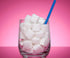 A glass with a blue plastic straw in filled with sugar cubes