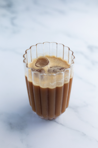 Glass with iced coffee, on marble surface