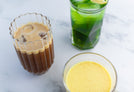 3 glasses of detox drinks; one contains iced coffee, one contains a turmeric drink, one contains a green drink with a lemon slice