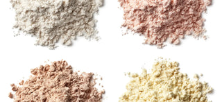 Four piles of protein powder are displayed on a white background